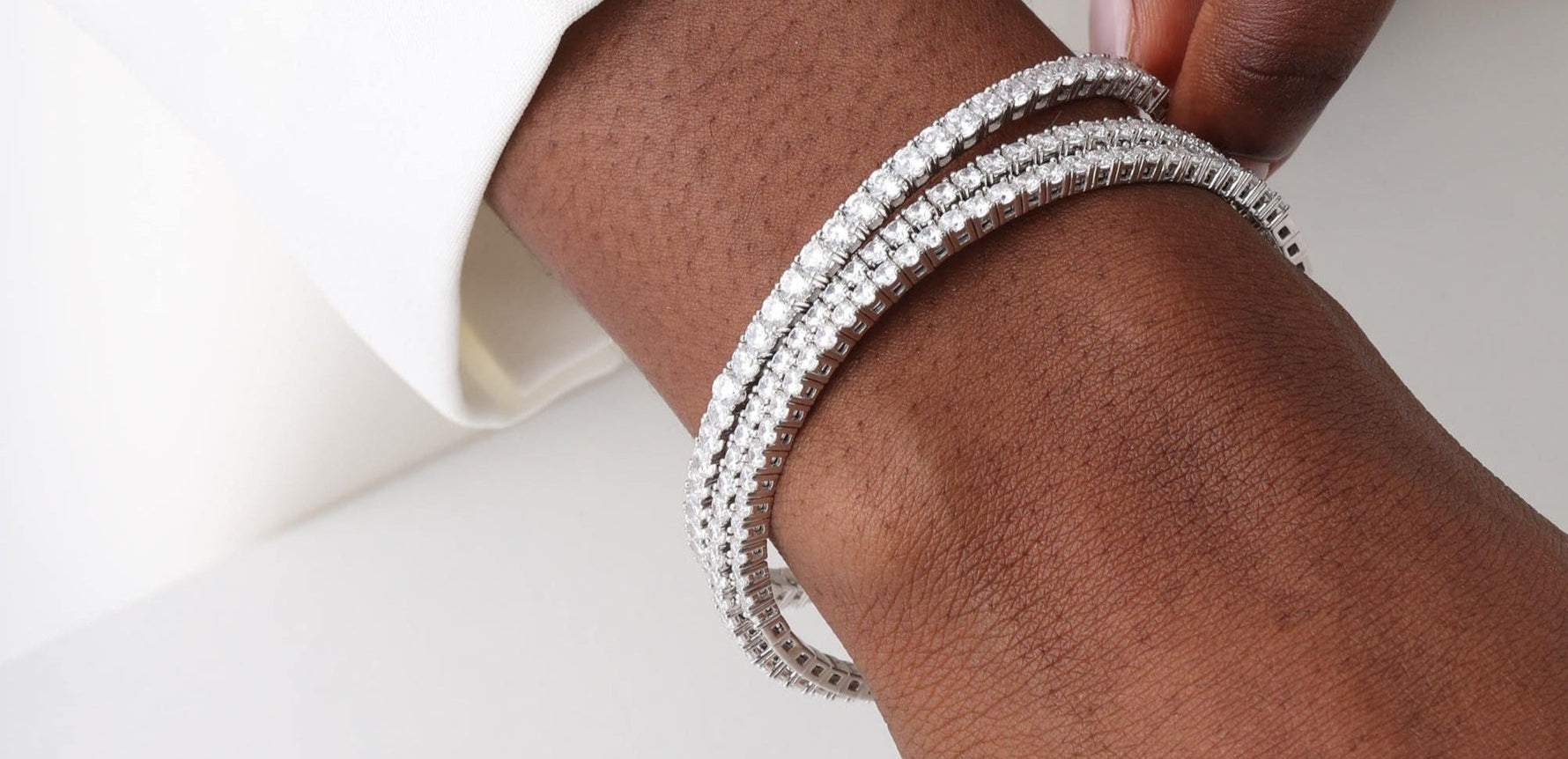 Close-up of a hand wearing a silver bracelet on a white background