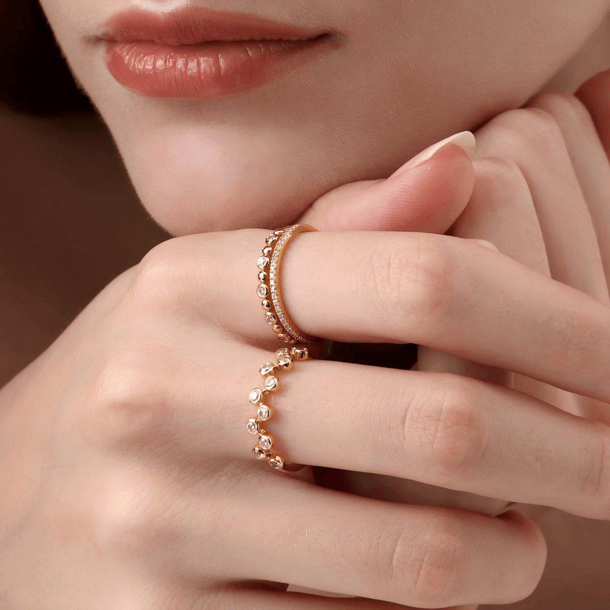 Close-up of a hand wearing two yellow gold rings with a soft focus background