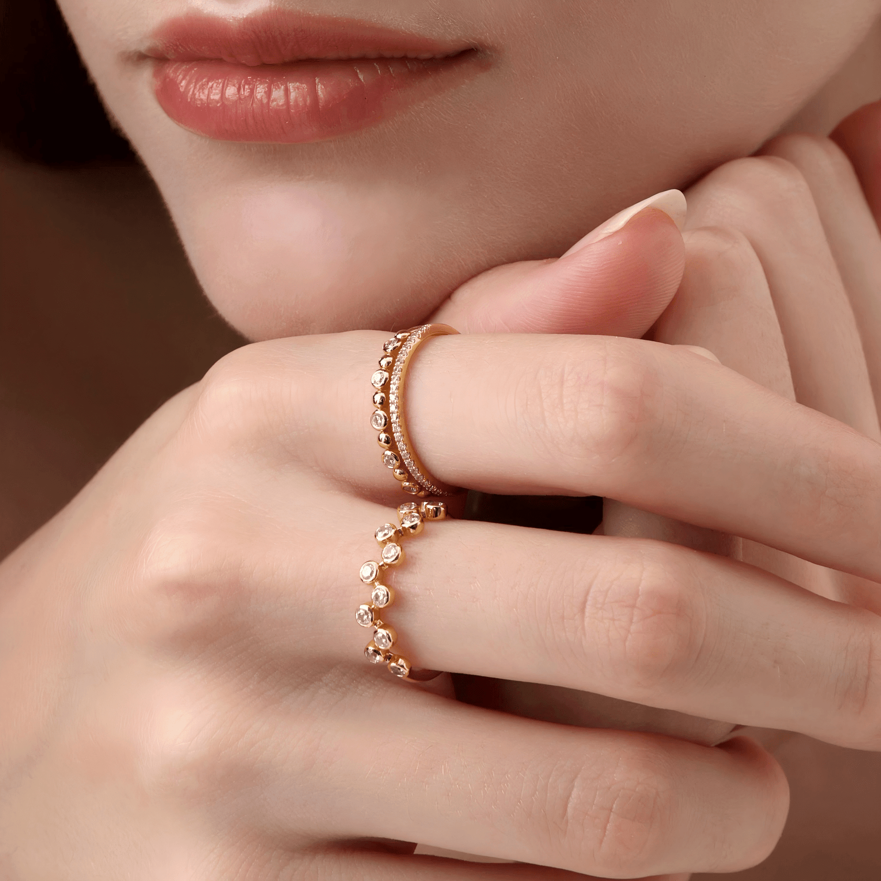 Close-up of a hand wearing two yellow gold rings with a soft focus background