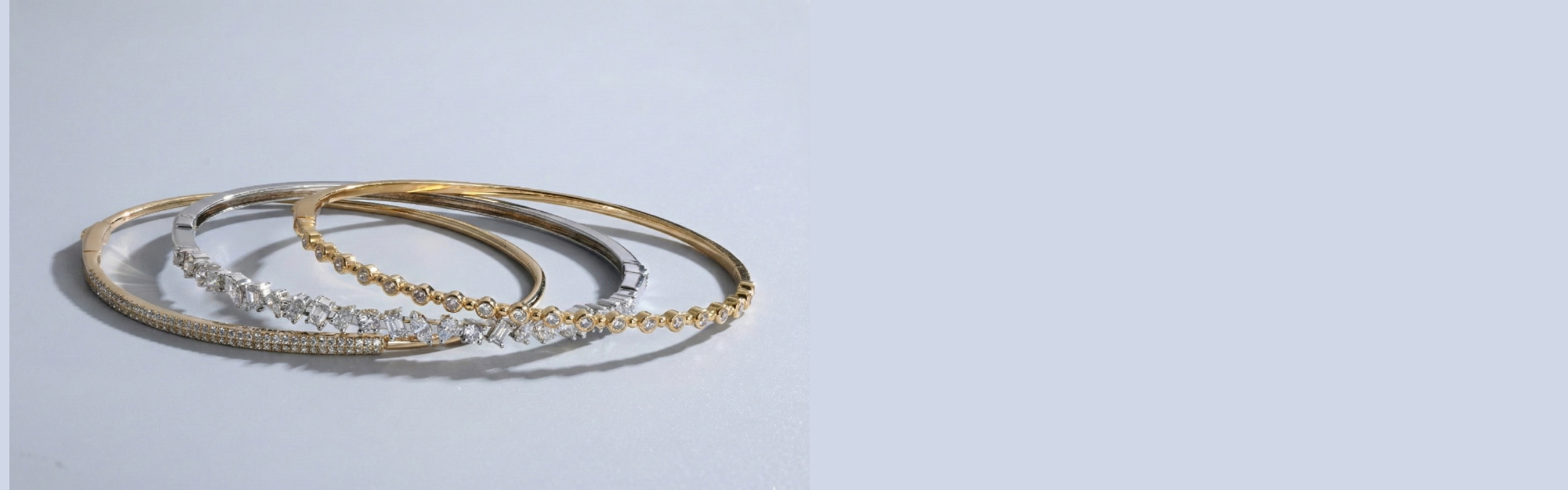 Set of gold and silver bangles on a light gray background