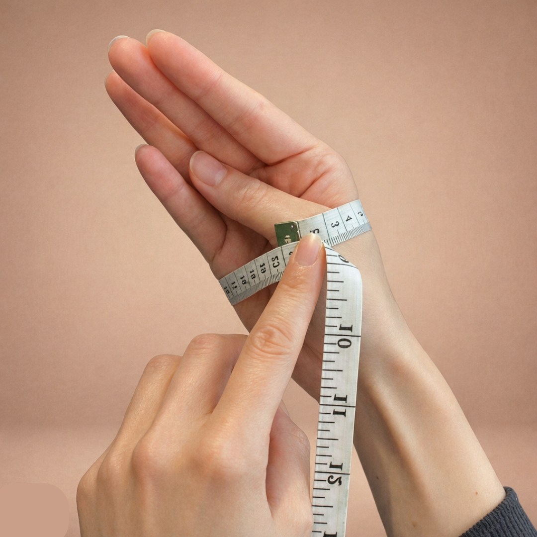Hand holding a measuring tape against a plain background