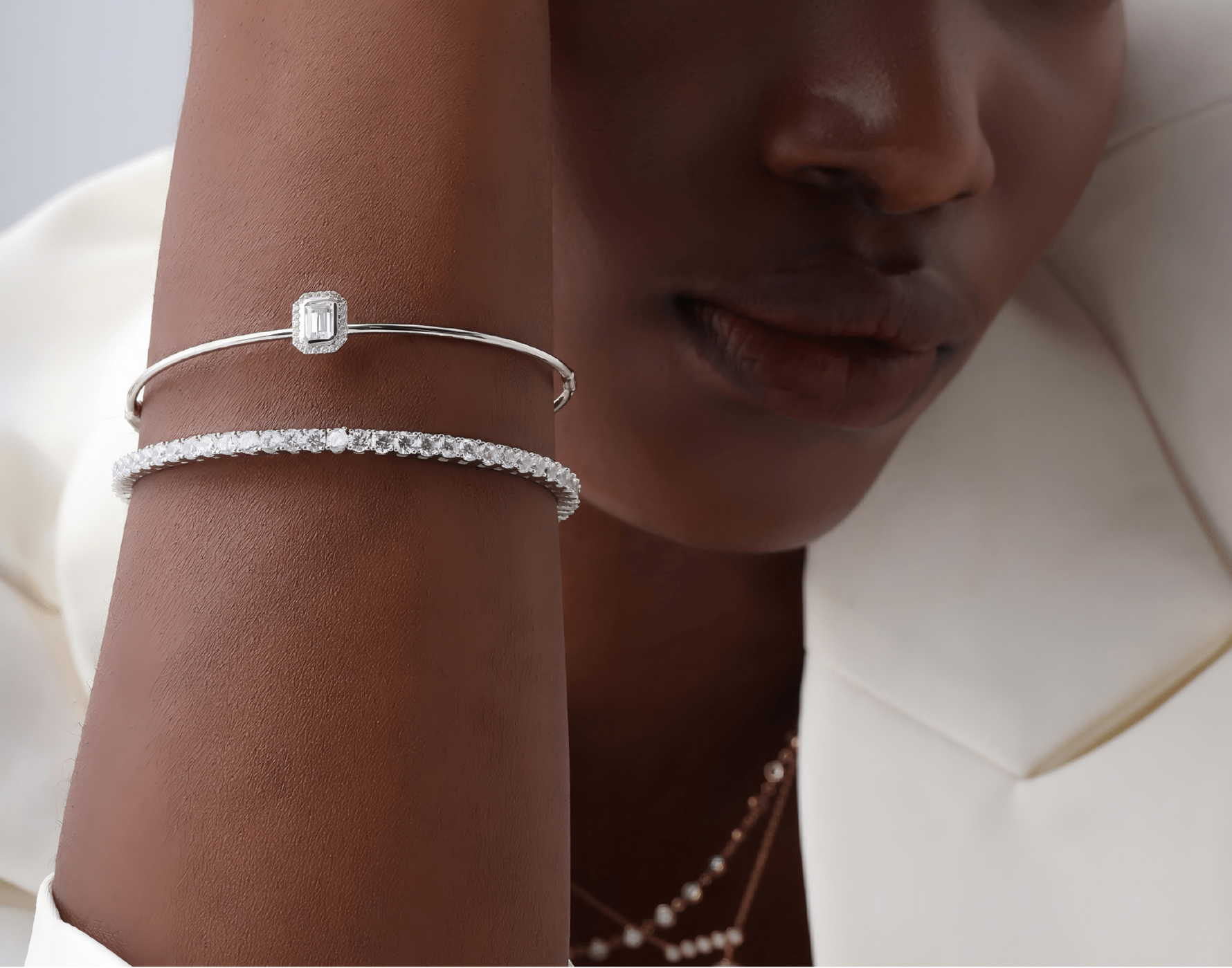 Woman wearing bangle bracelets on a plain background