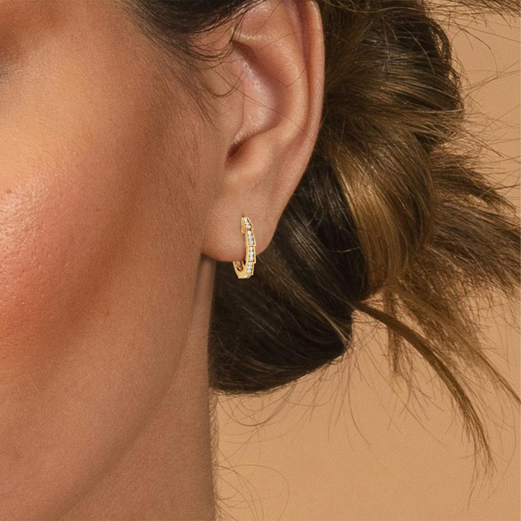 Close-up of an ear wearing a 14mm diameter gold and diamond earring with a blurred background