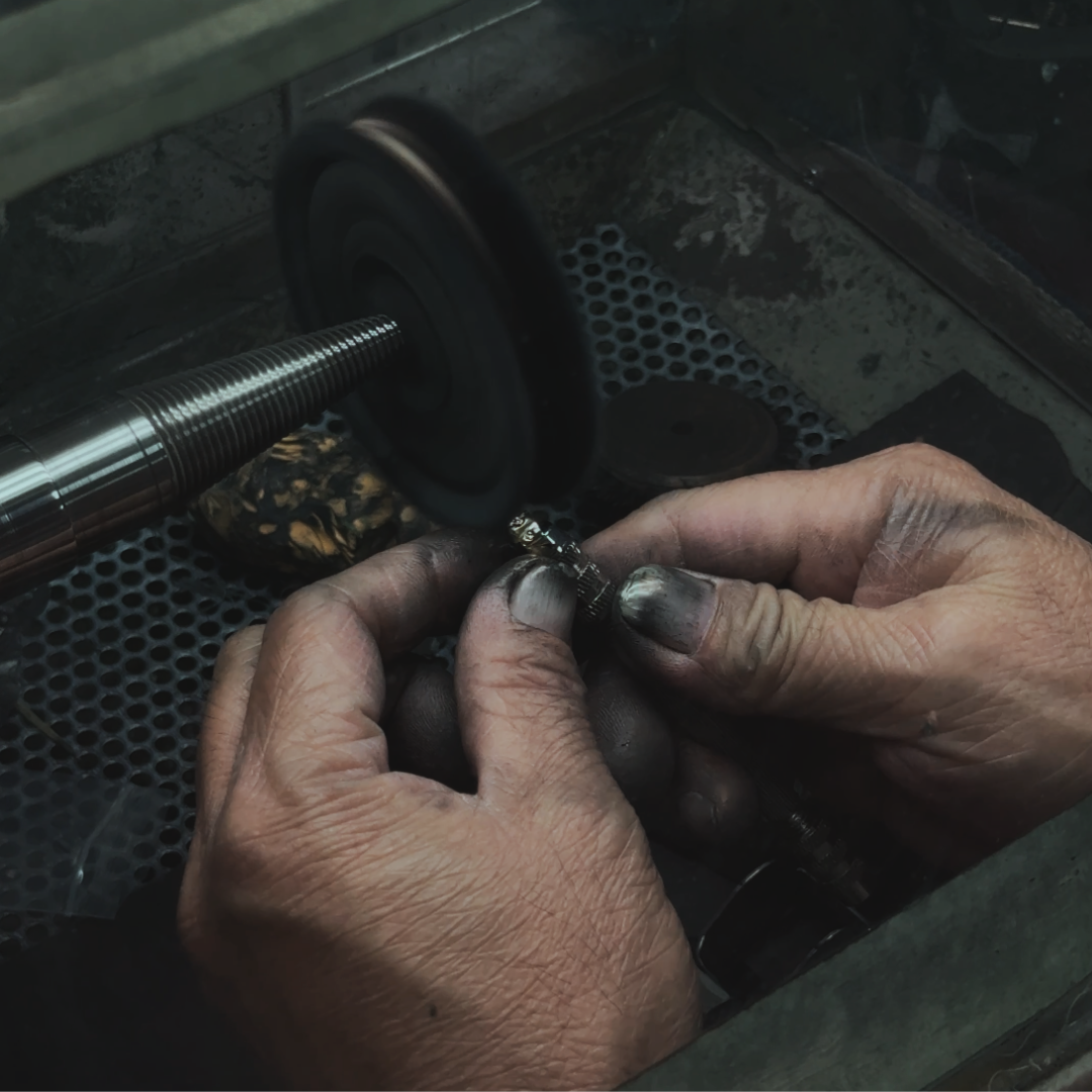 Close-up of hands working on a jewelry component with tools in the background