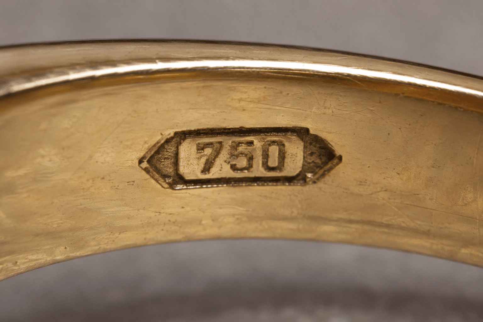Close-up of a 750 hallmark stamped inside a gold ring indicating 18K gold purity.